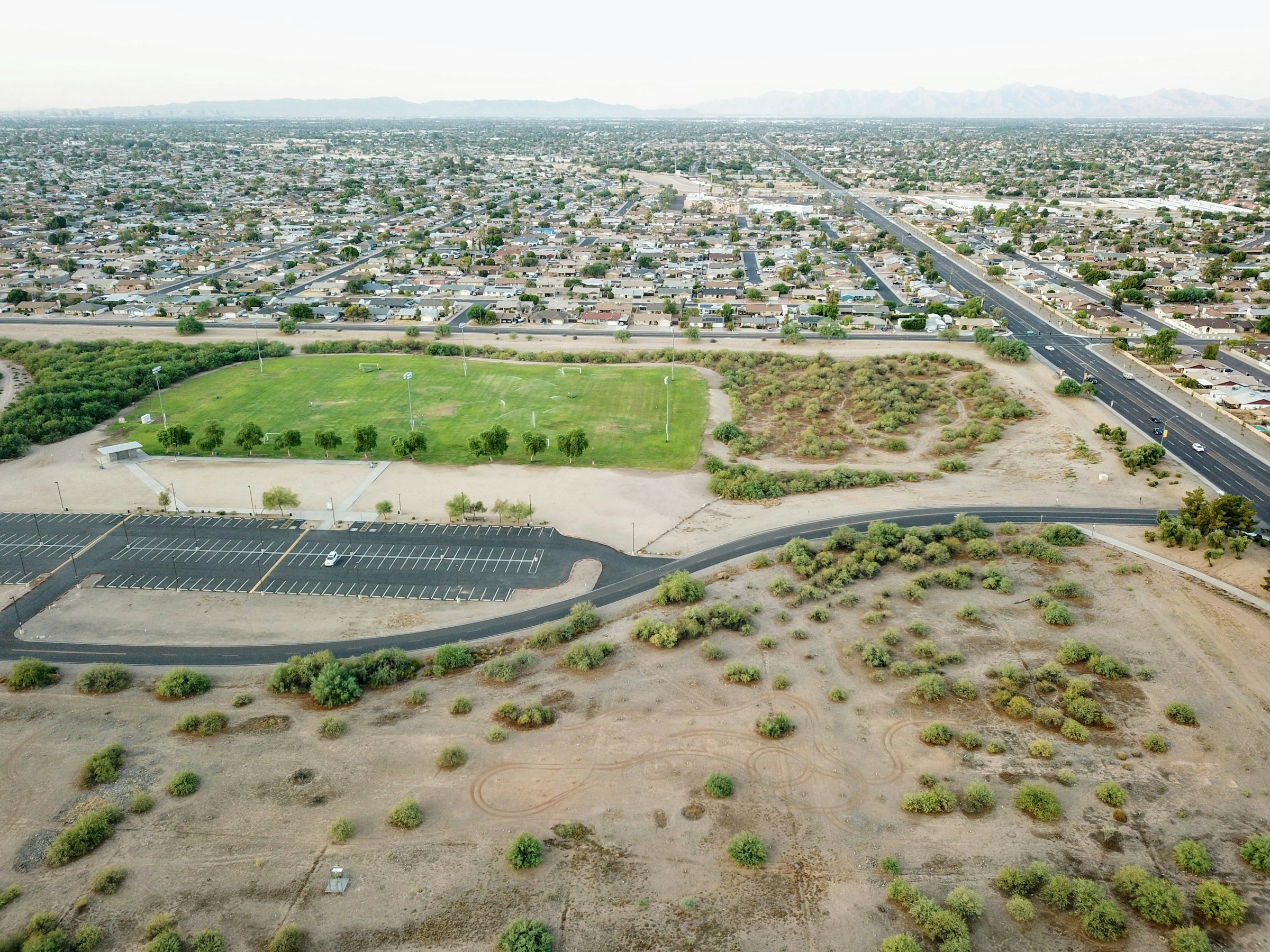 Aerial view of undeveloped land beside a highway and parking area